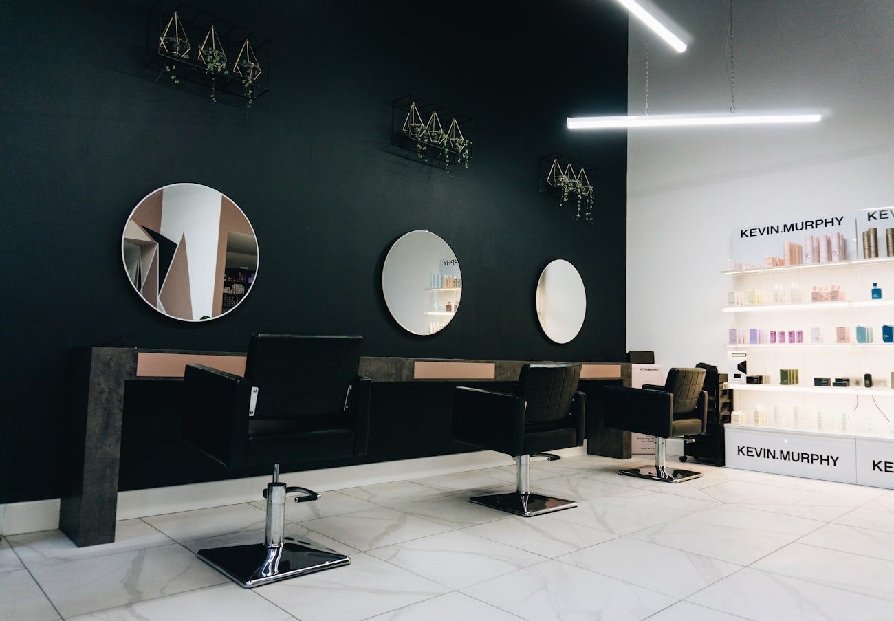 A modern salon interior with round mirrors and a retail shelf of products