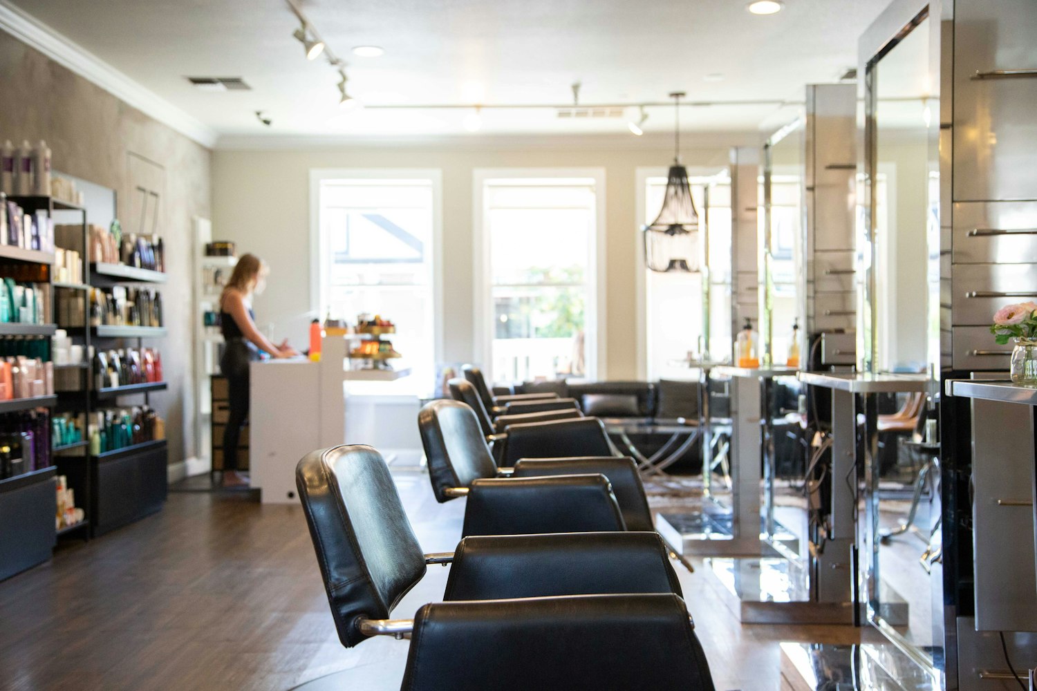 A bright, welcoming hair salon interior with styling chairs and a member of staff at the front desk